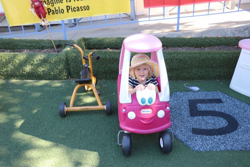 A toddler riding a toy car on the playground