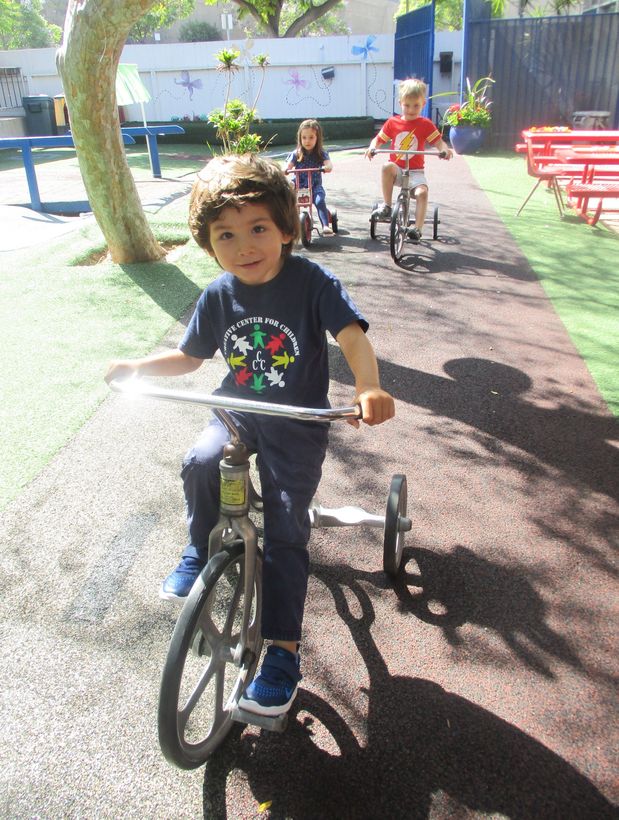 A child riding a tricycle along the garden bike path