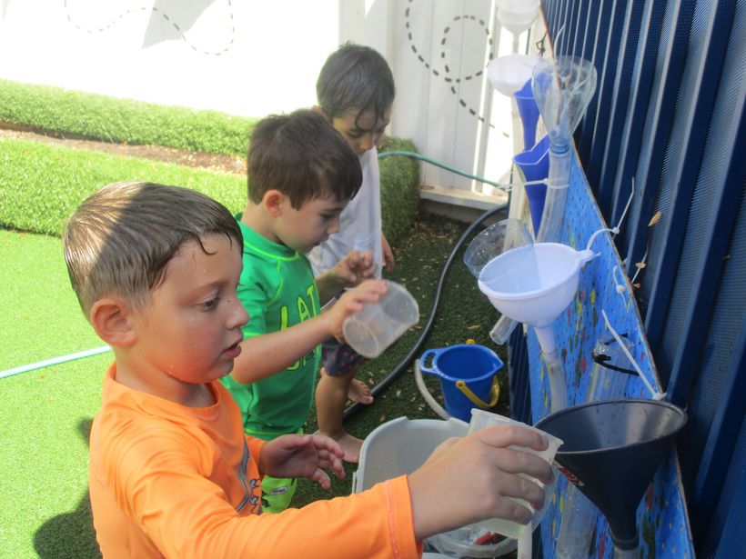 Preschoolers exploring a water and funnel science activity