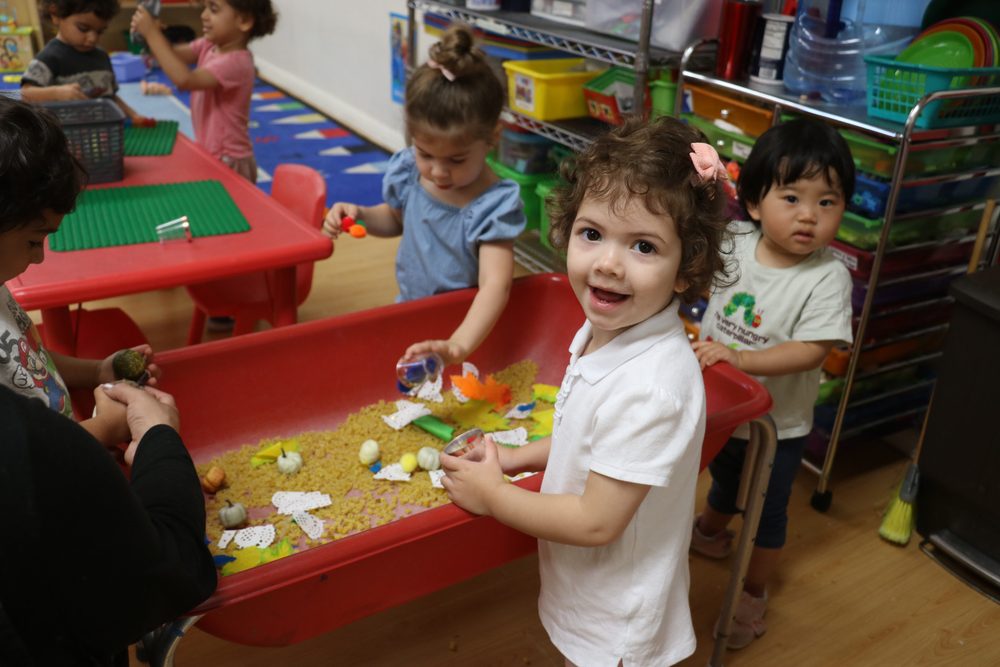 Two-year-olds playing at sensory tables in the Tadpoles classroom