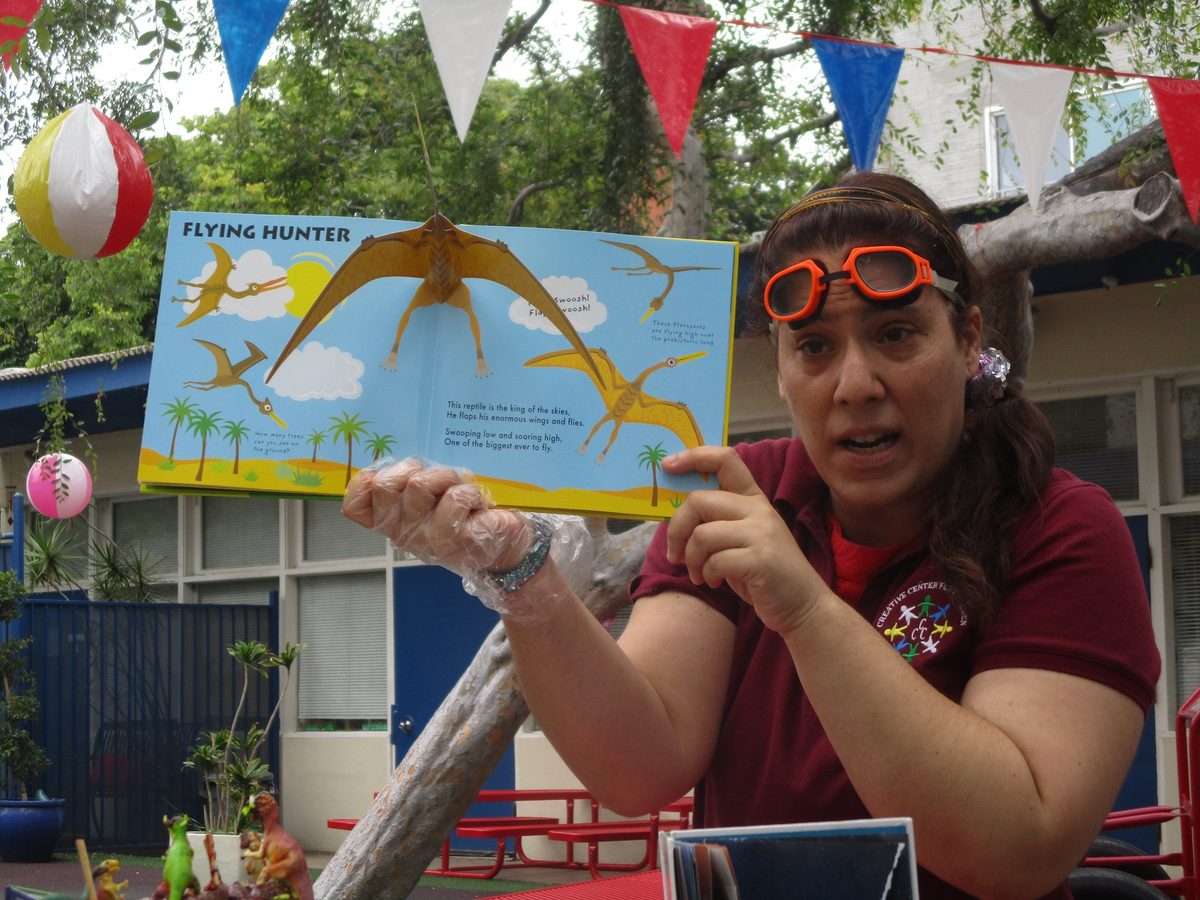 A teacher reading to three-year-olds outdoors in the Fireflies class